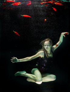 Adolescent girl underwater - surreal floating chillies