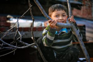 Small boy on a tree with bare branches, urban