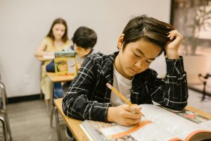 Young boy with other children doing an exam at school