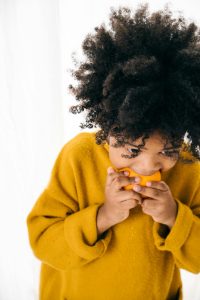 Young girl eating a ripe orange